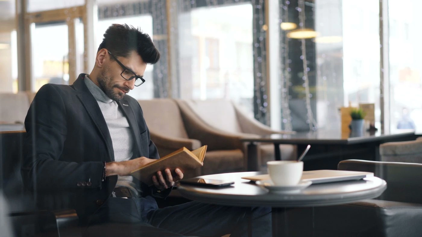 A reader taking time to study a book in a naturally lit café